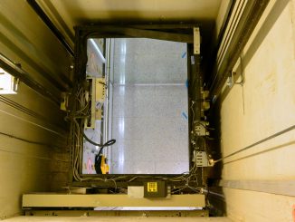 Fahrkorb mit geöffneter Dachluke in einem Aufzugsschacht.